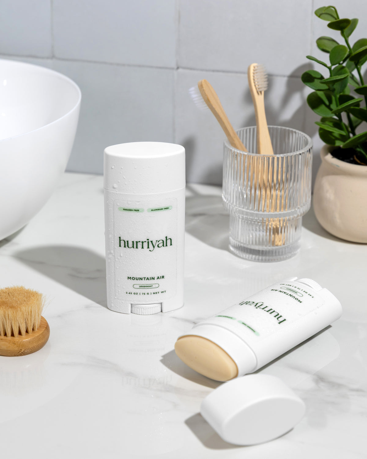 Hurriyah Mountain Air deodorant on a marble bathroom counter with a brush and plant