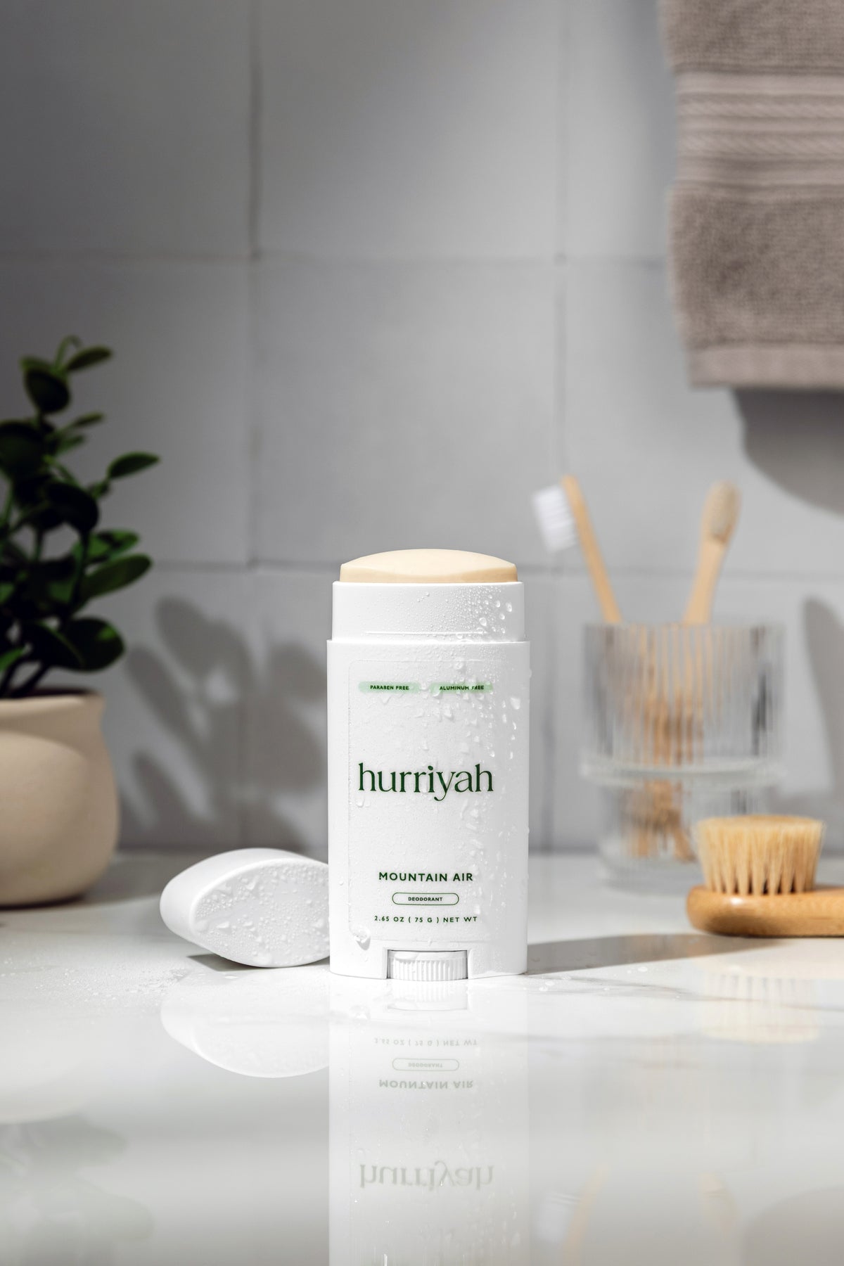 Hurriyah Mountain Air deodorant on a marble counter beside toothbrushes and a plant